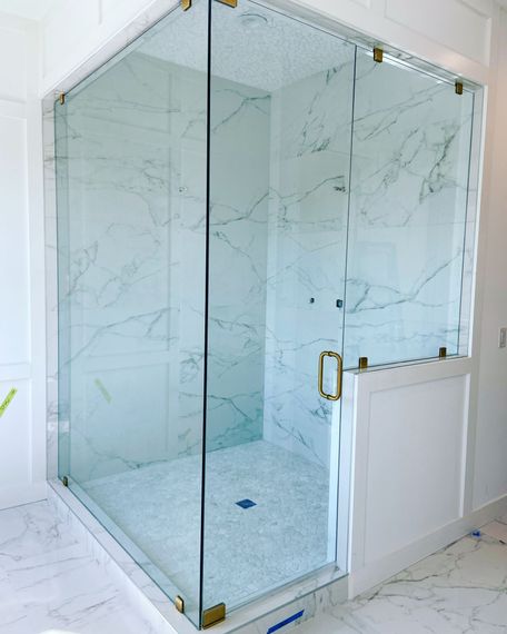 A bathroom with a walk in shower with a glass door.