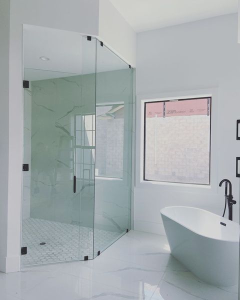 A bathroom with a tub , shower , and window.