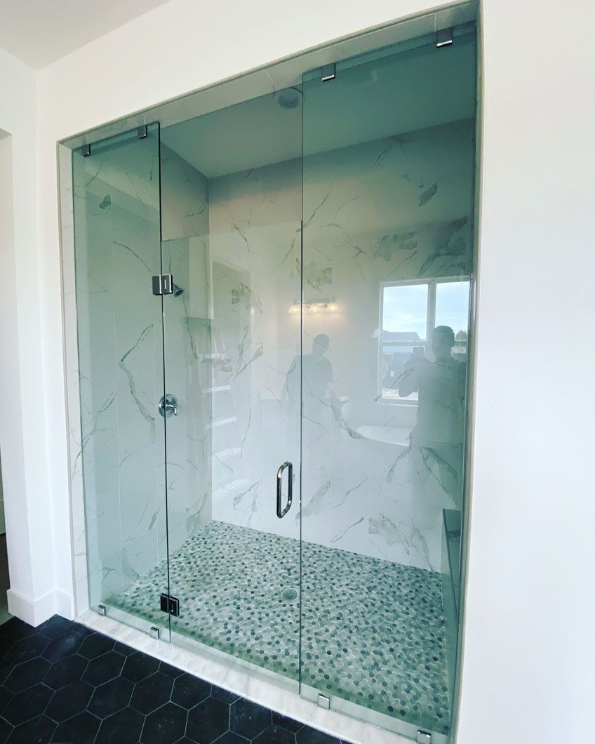 A bathroom with a walk in shower with a glass door.