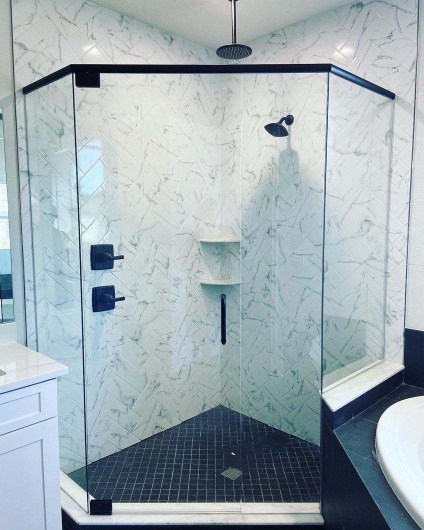 A bathroom with marble walls and a glass shower door