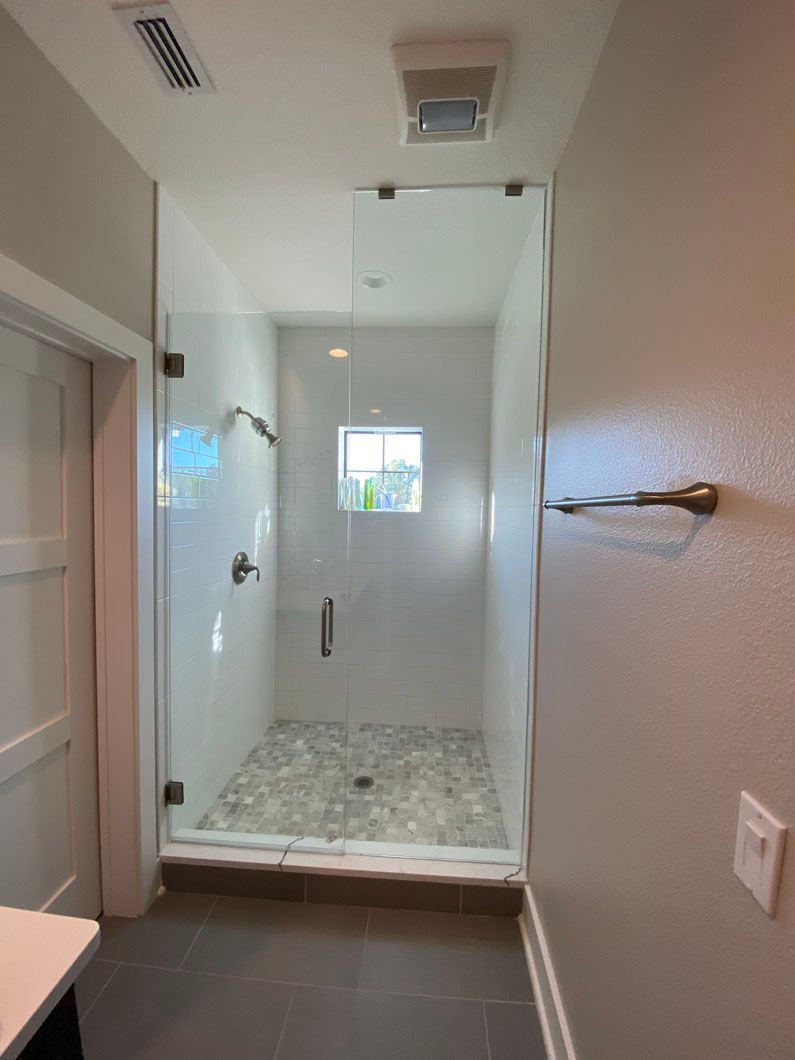 A bathroom with a walk in shower with a glass door.
