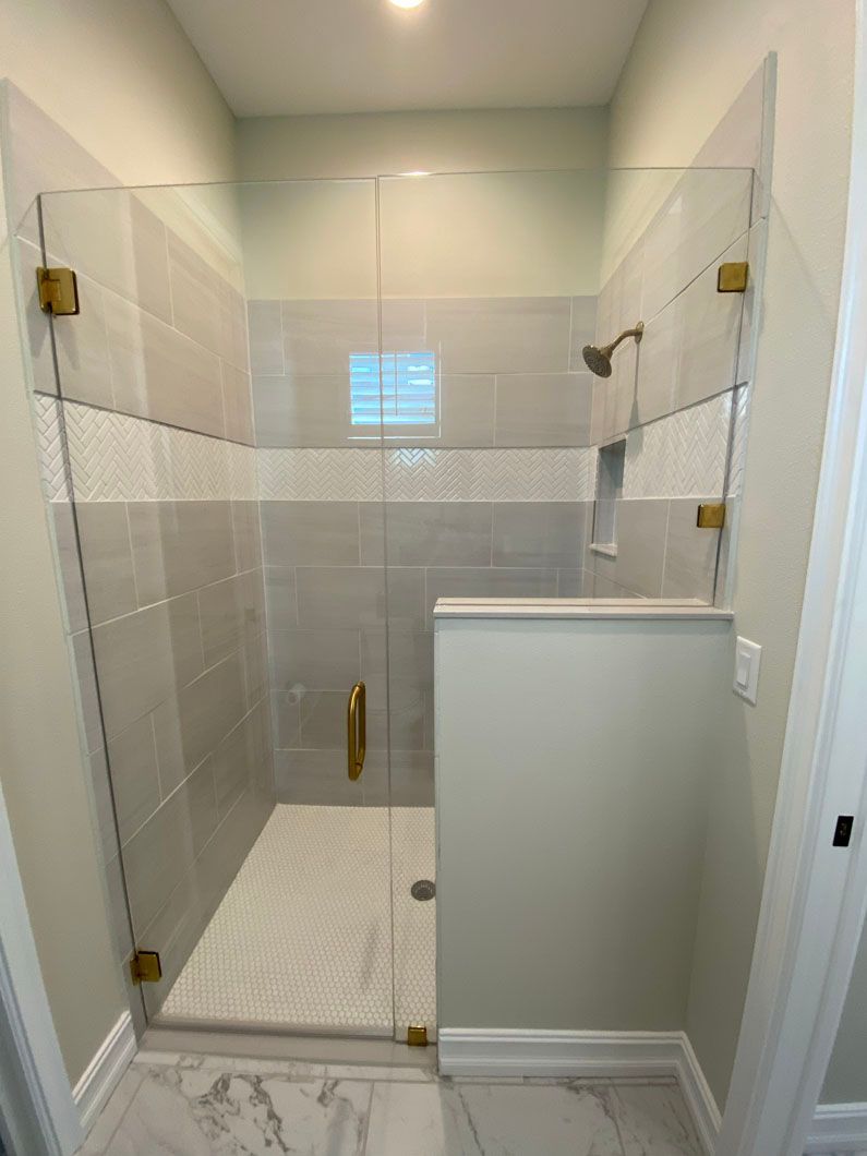 A bathroom with a walk in shower with a glass door.