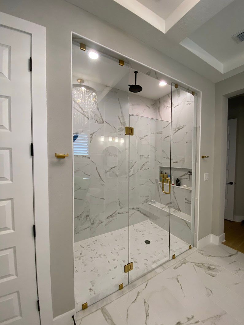 A bathroom with a walk in shower with a glass door.