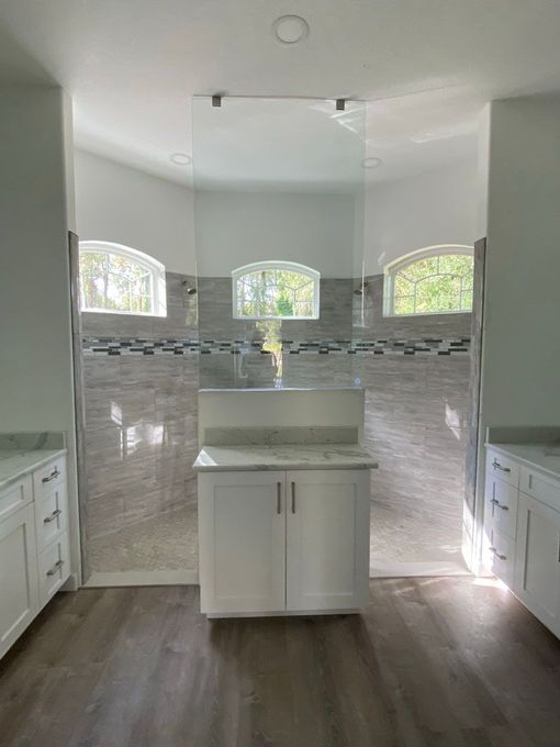 A bathroom with two sinks and a walk in shower.