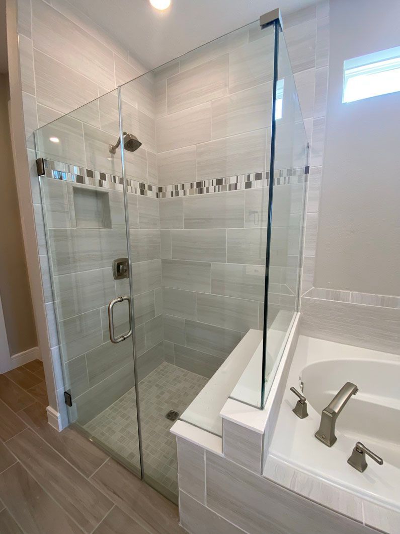 A bathroom with a walk in shower and a tub.
