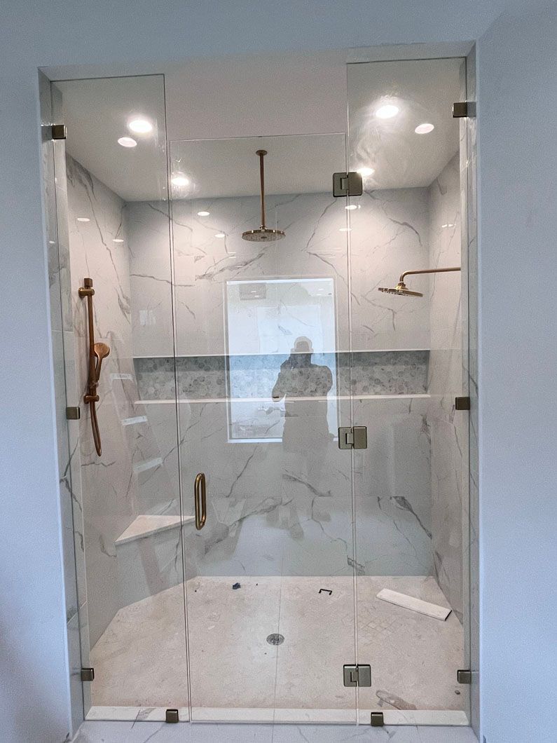 A bathroom with a walk in shower with a glass door.