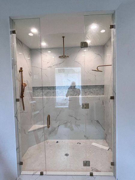 A bathroom with a walk in shower with a glass door.