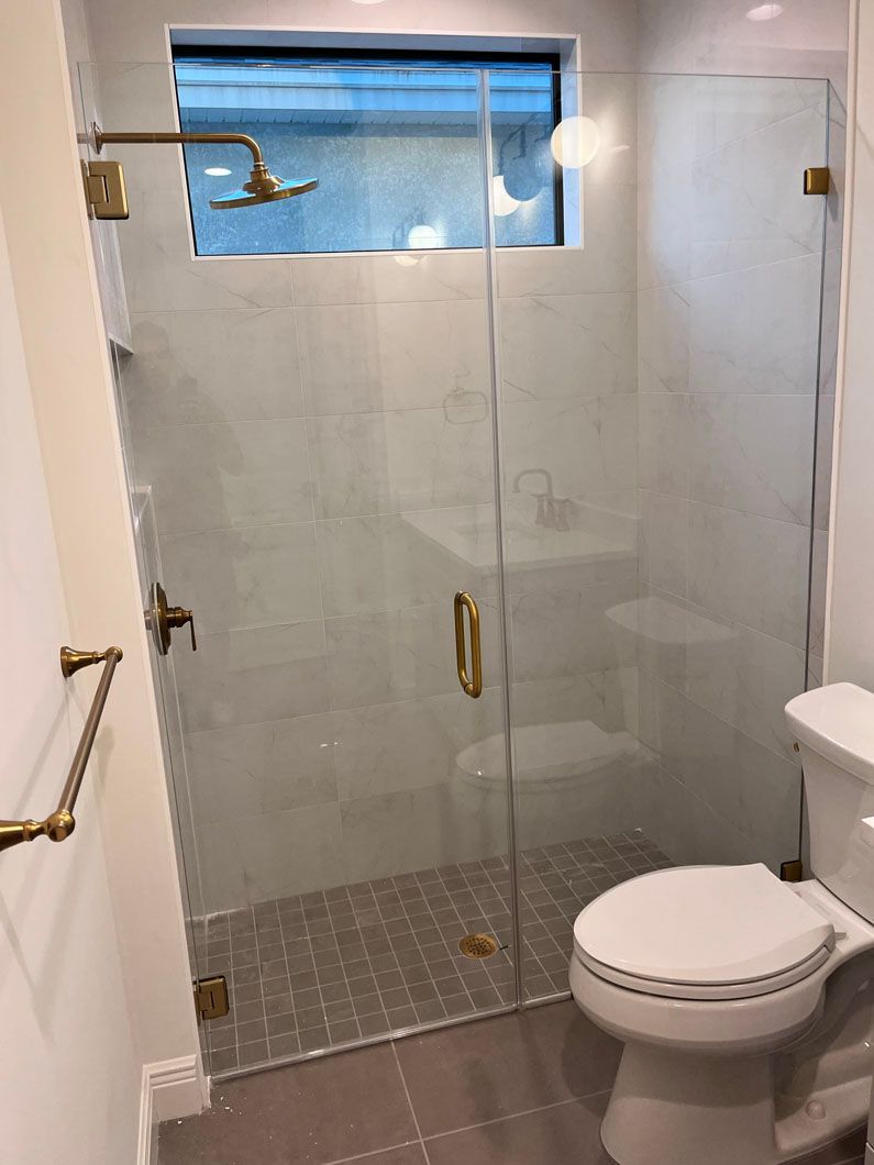 A bathroom with a toilet , sink , shower and glass door.