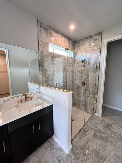 A bathroom with a sink , mirror and walk in shower.