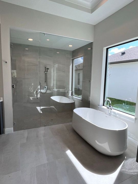 A bathroom with a tub , shower , and window.