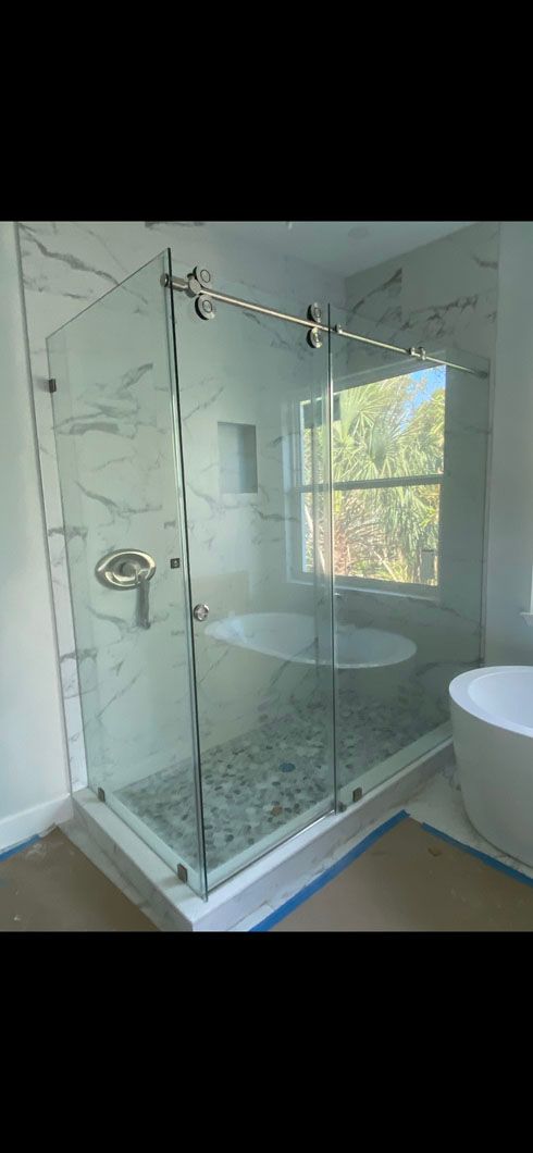 A bathroom with a sliding glass shower door and a bathtub.