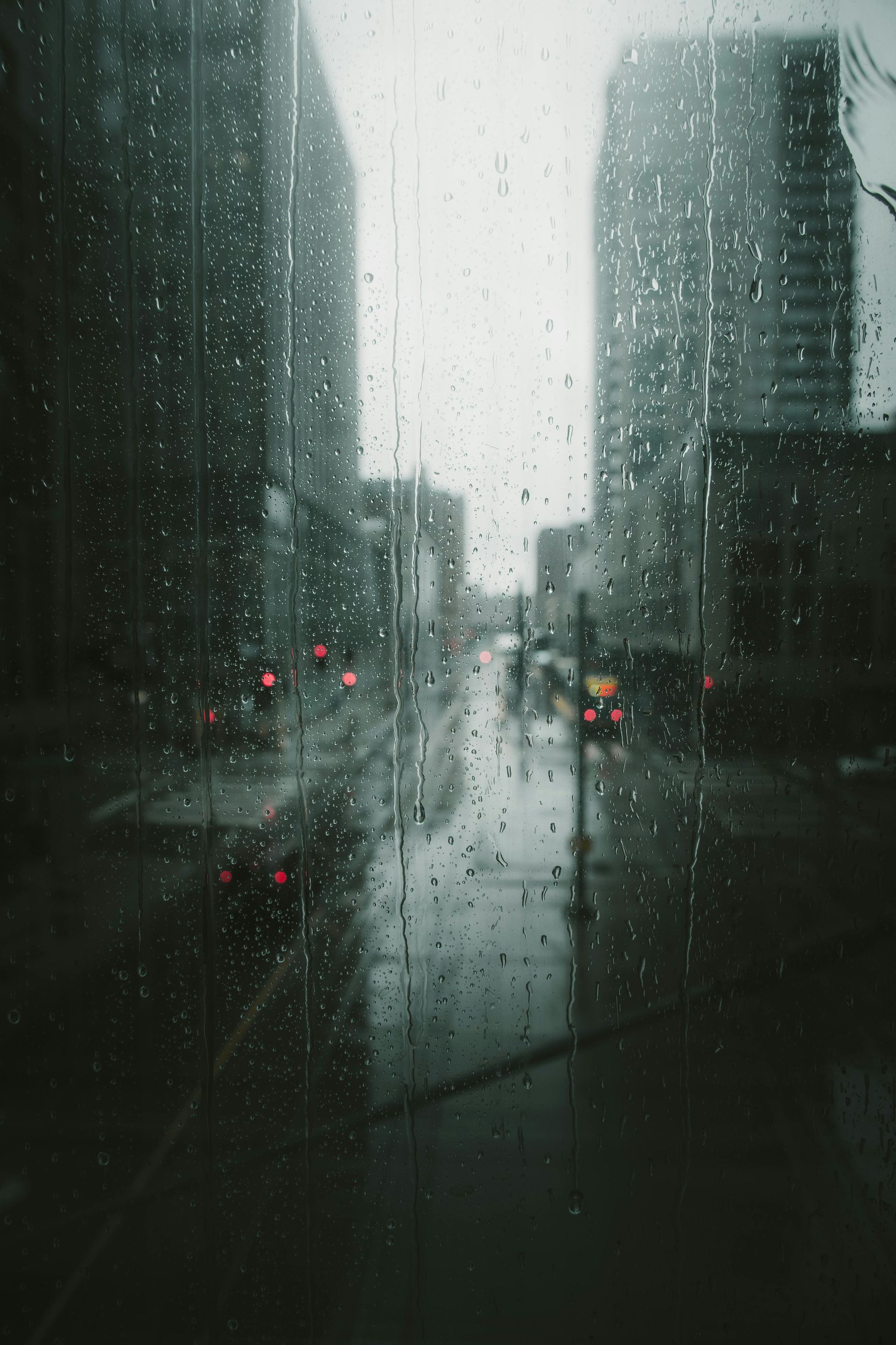 A view of a city street through a window with rain drops on it.