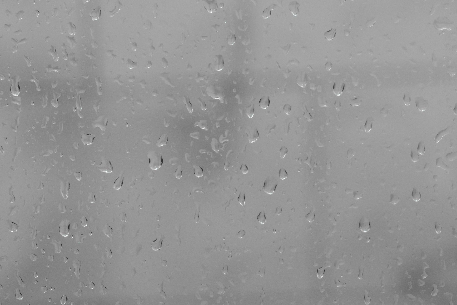 A black and white photo of rain drops on a window.