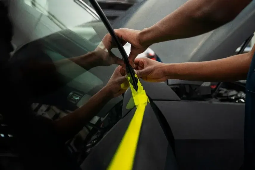 A person is wrapping a car with yellow tape.