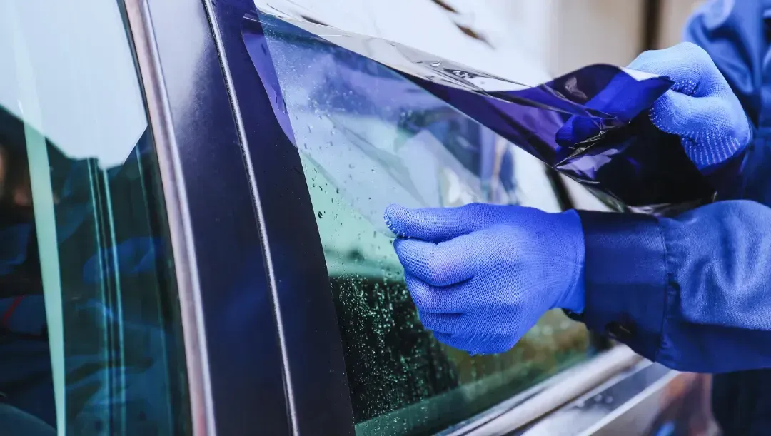 A person is applying tinted glass to a car window.