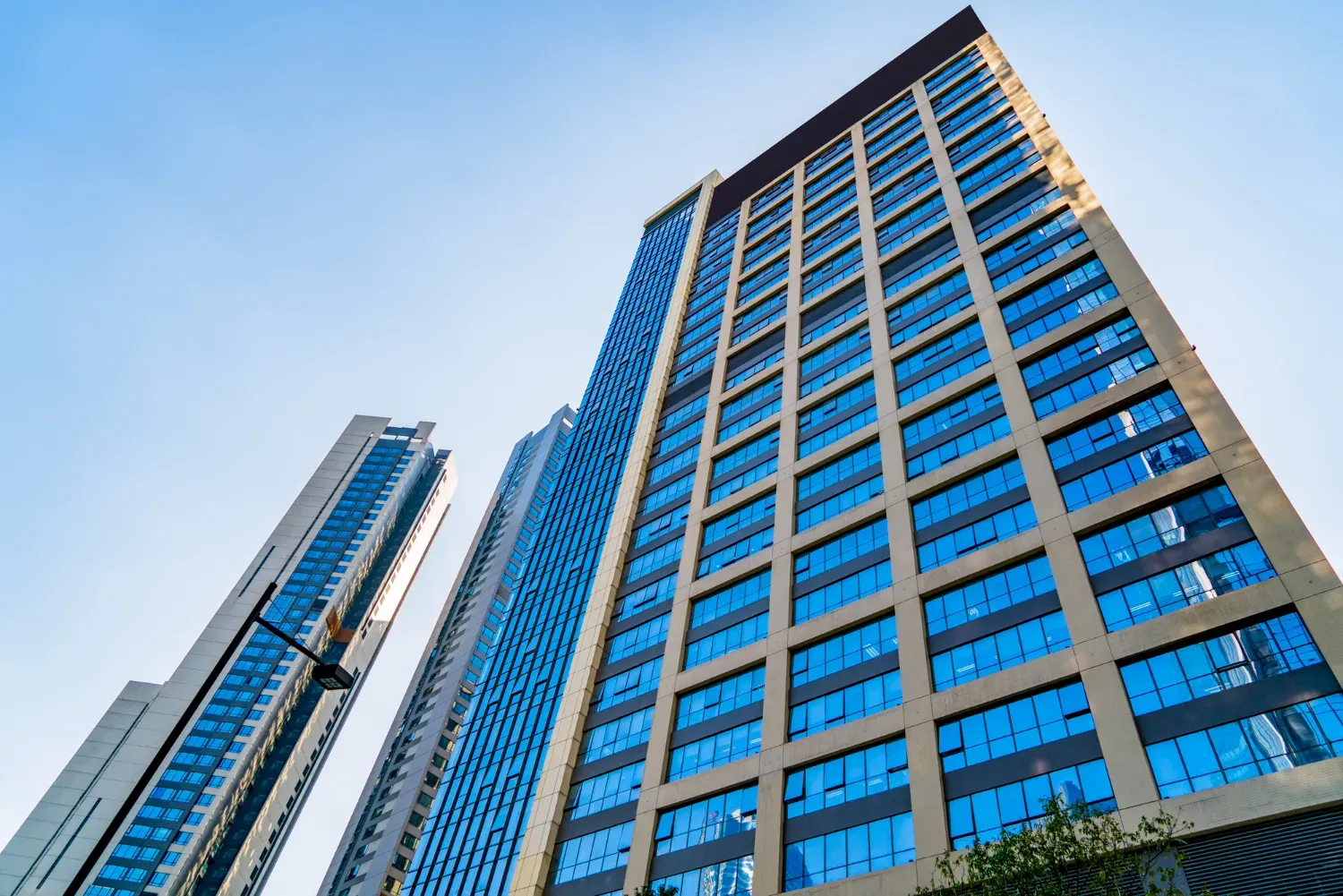 Looking up at a tall building with lots of windows against a blue sky.