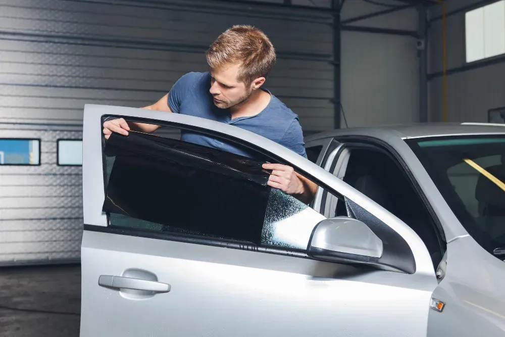 Window Tint - A man is applying window tinting to a car window.