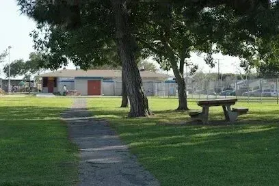 Window Tinting Service-Park with a building, path, picnic table, and trees on a sunny day.