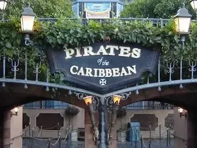 Window Tinting Service-Entrance sign for Pirates of the Caribbean ride at Disneyland with ornate metalwork and green foliage.