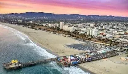 Window Tinting Service - An aerial view of a pier on a beach with a city in the background.