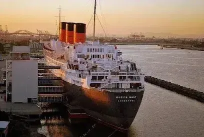Window Tinting Service-Queen Mary ocean liner docked in a harbor, three red and black smokestacks, sunset, California.