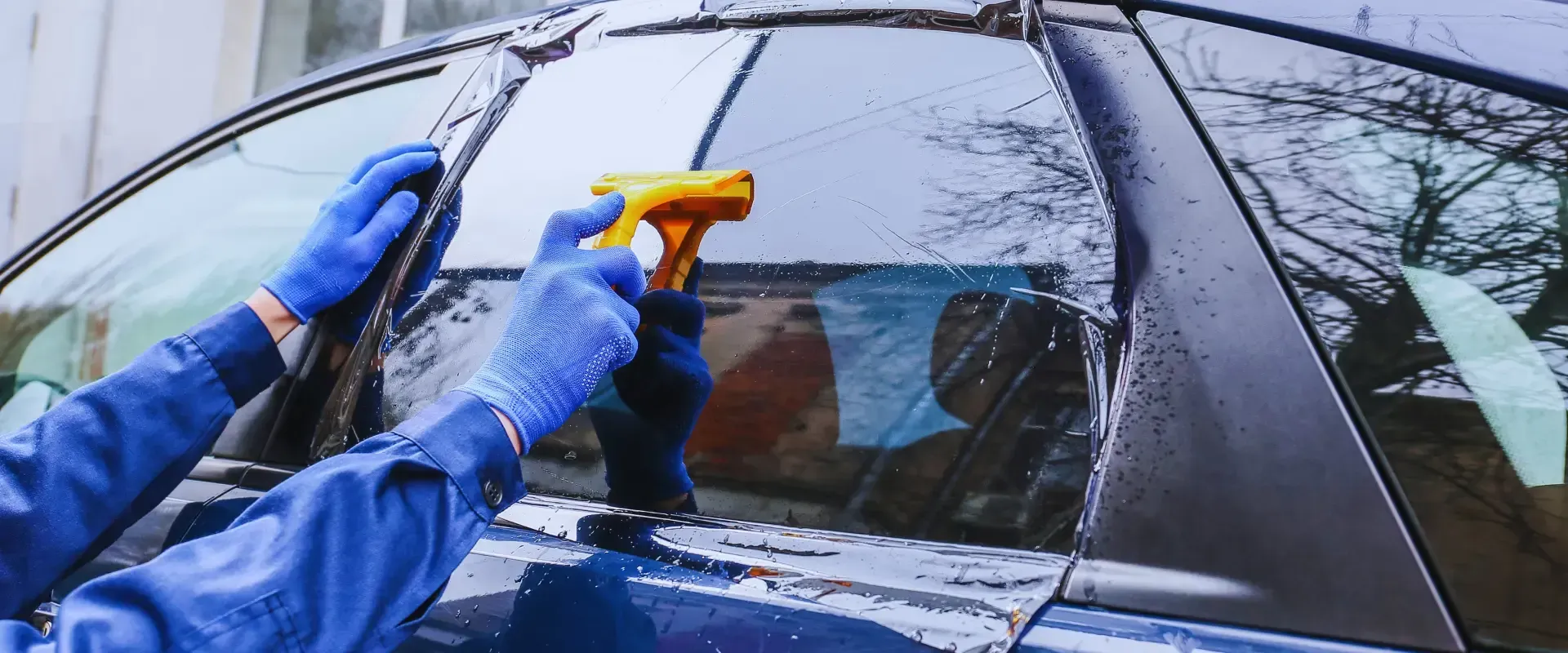 A person is cleaning the windshield of a car with a spray bottle.