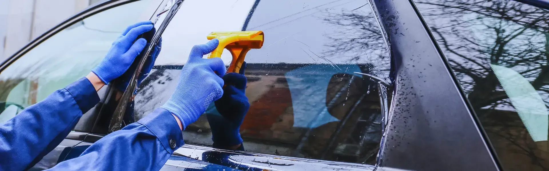 A person is cleaning the windshield of a car with a spray bottle.