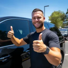 a man giving a thumbs up in front of a car showing work well done