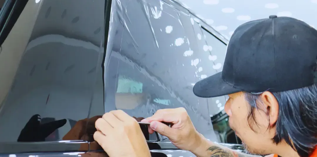 A man is applying tinted glass to a car window.