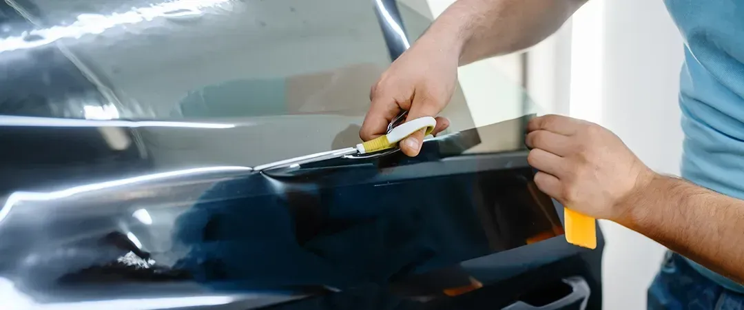 A man is applying tinted glass to a car window.