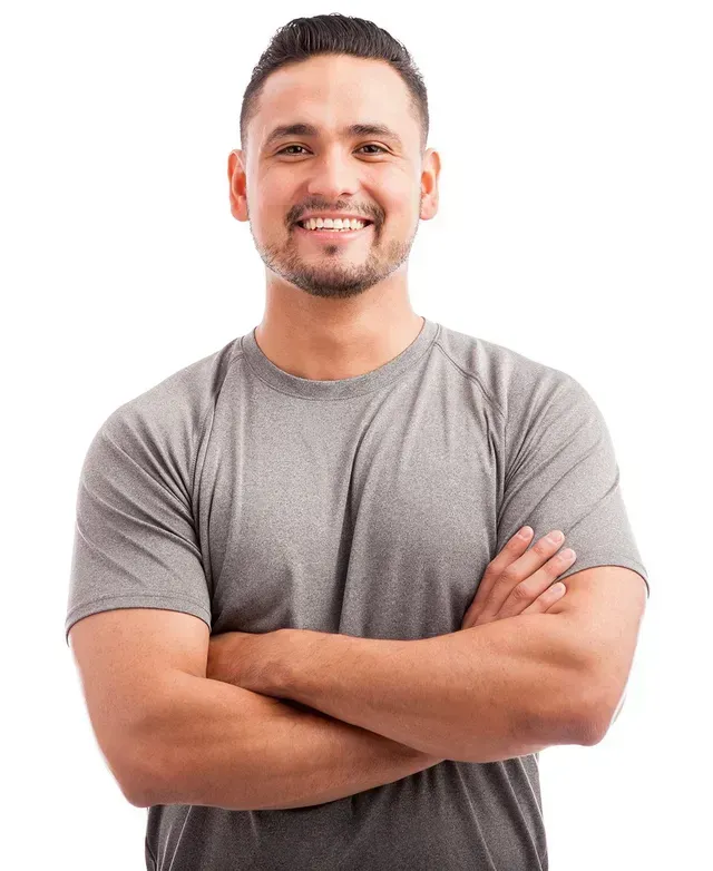 A man in a grey shirt is smiling with his arms crossed