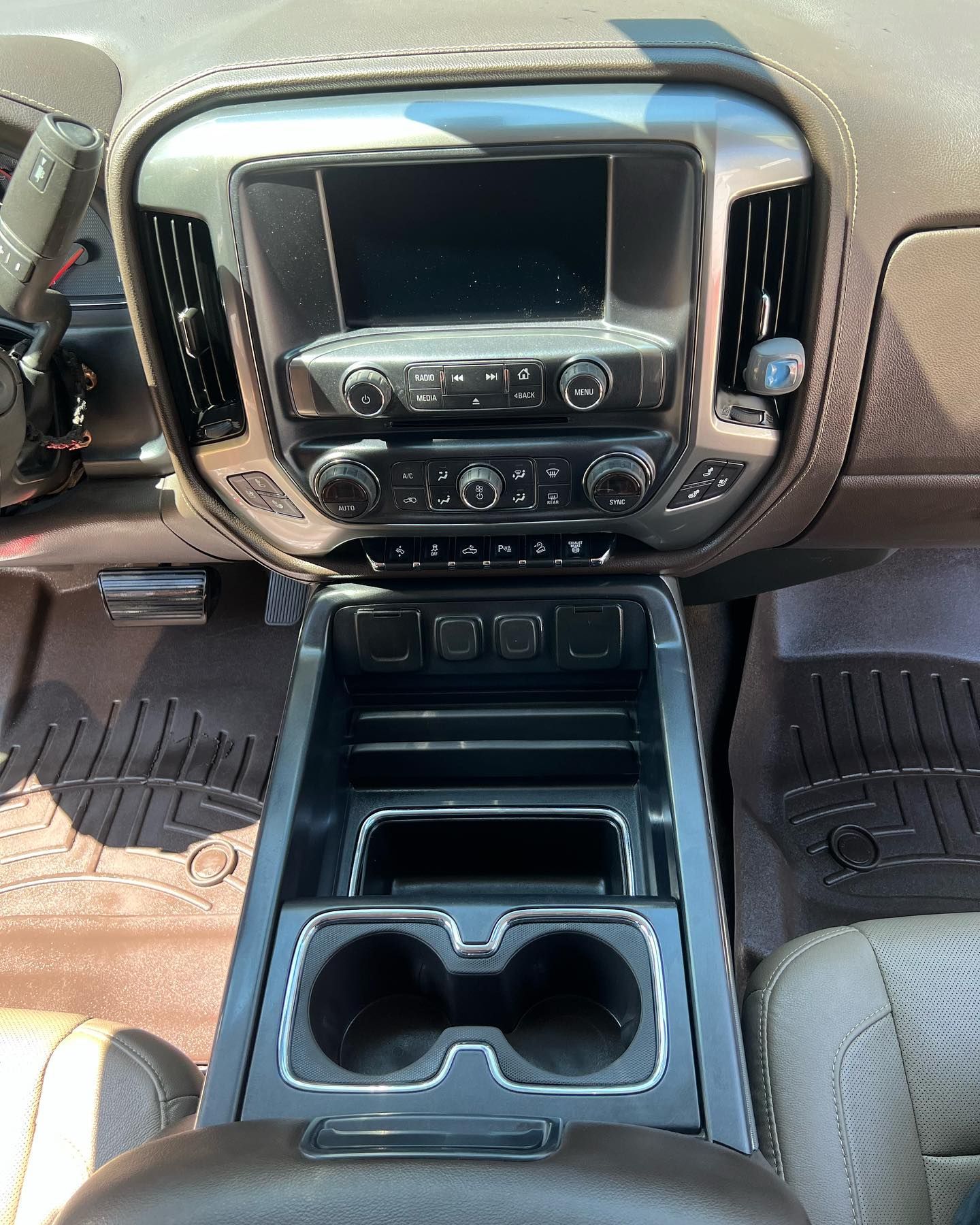 The dashboard of a car with a cup holder and a radio.