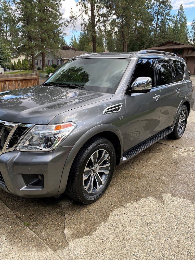 A gray suv is parked in a driveway next to a house.