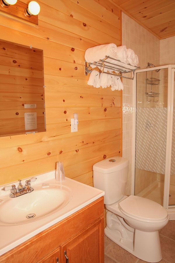 A bathroom with a toilet , sink and shower.