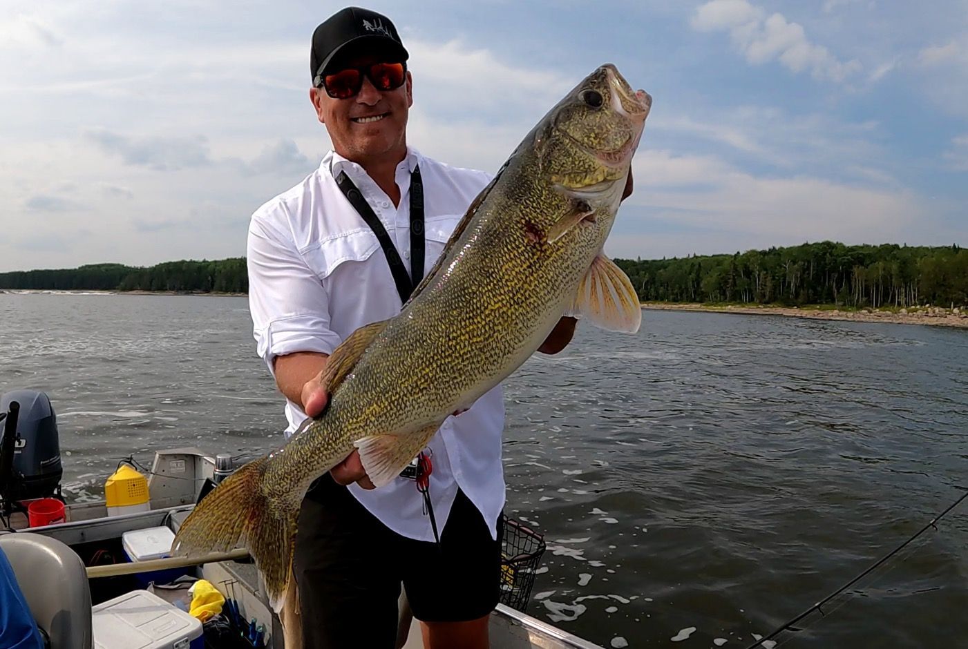 Taylor is holding a large walleye fish on a boat.