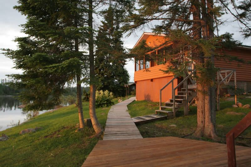 A wooden walkway leads to a cabin with stairs leading up to it