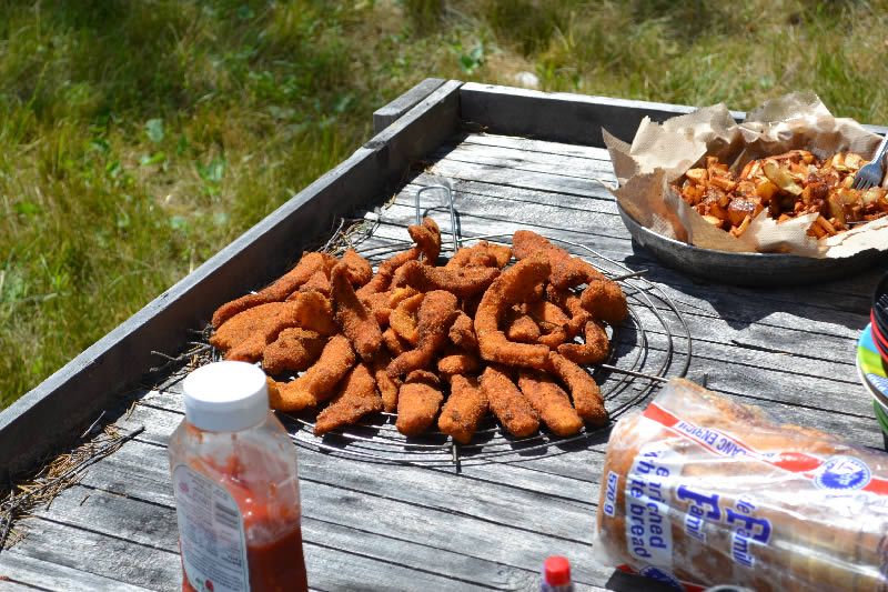 A wooden table with fried food and a bag of bread