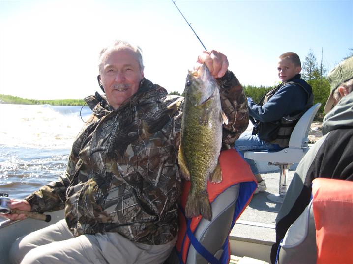Fisherman holding a smallmouth bass at his fly-in fishing trip to Canada