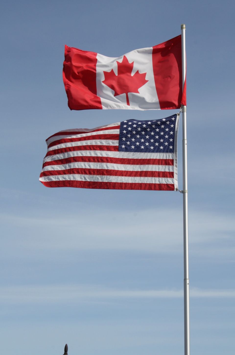 A canadian flag and an american flag are flying side by side