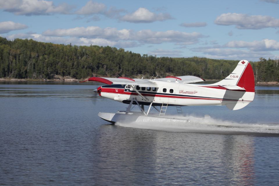 A red and white float plane is taking off from the water.