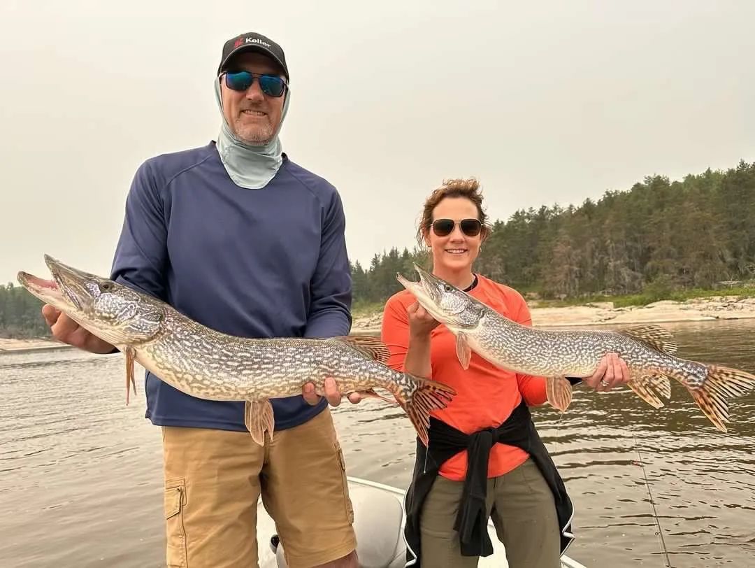Michelle and Cory are holding up northern pike on their fishing trip to Oak Lake Lodge.