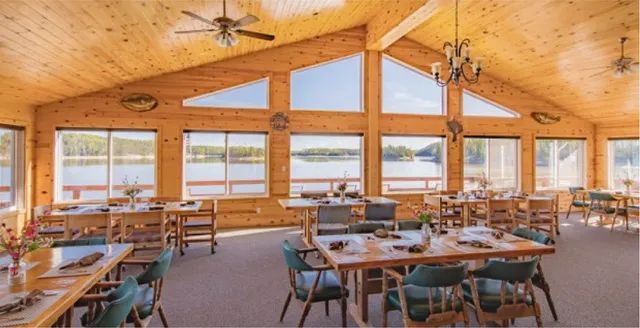 Oak Lake Lodge's dining hall with large glass windows looking out to the lake.