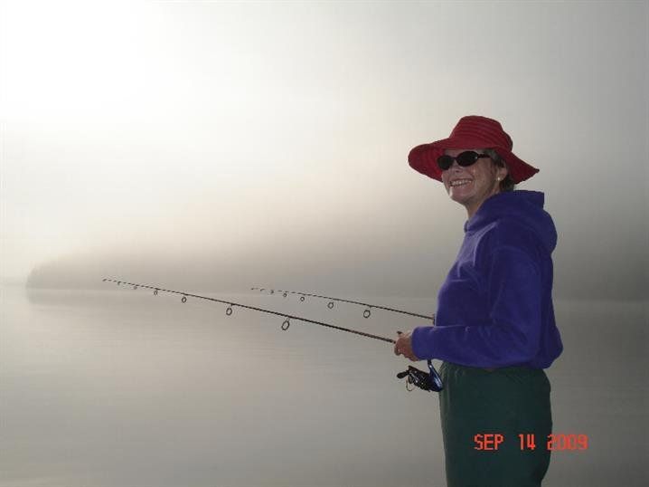Woman fishing on the lakeshore in the misty morning.