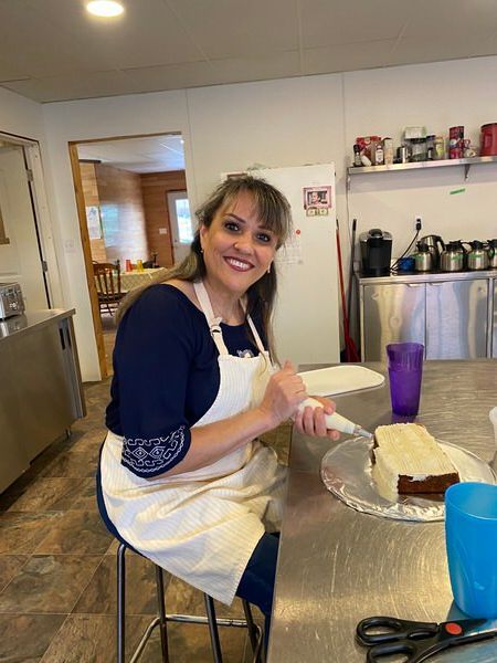 A woman is sitting at a table with a piece of cake on it.