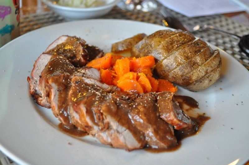 A white plate topped with meat and vegetables on a table.