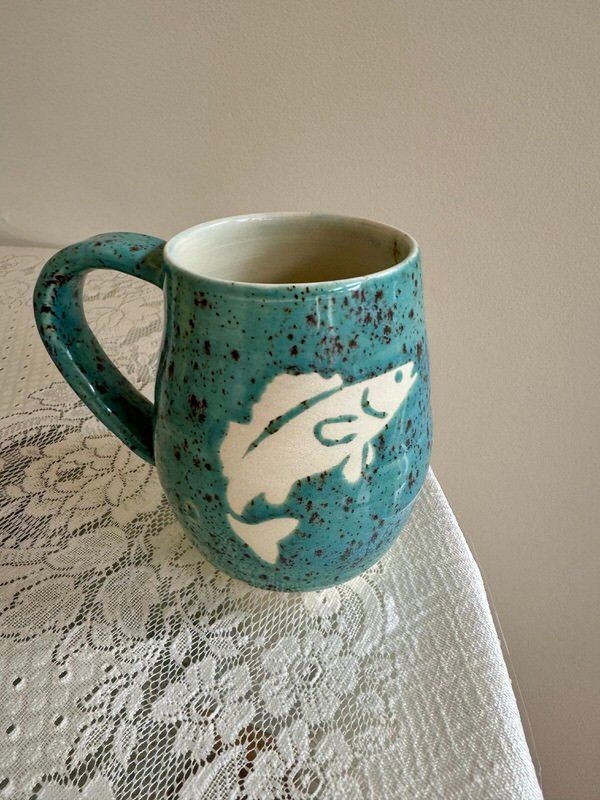 A blue mug with a white fish on it