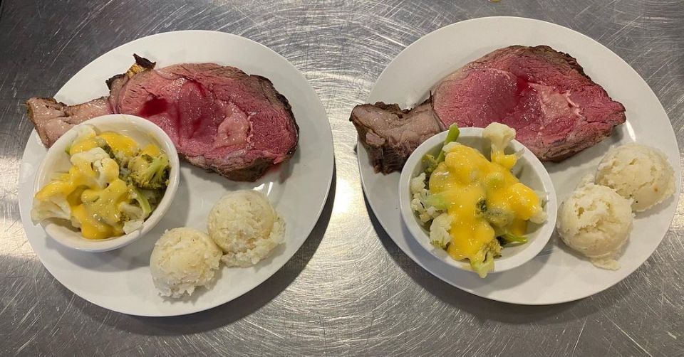 Two plates of food with meat and vegetables on a table.