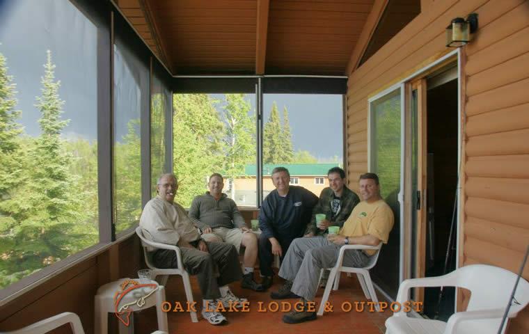 A group of friends after their day of fishings sitting in the screened-in porch of their fishing cottage.