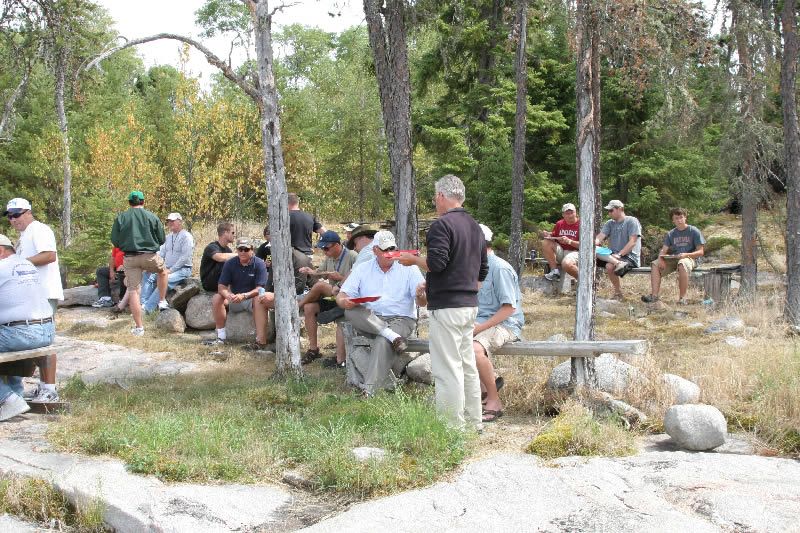 A group of men are sitting on benches in the woods