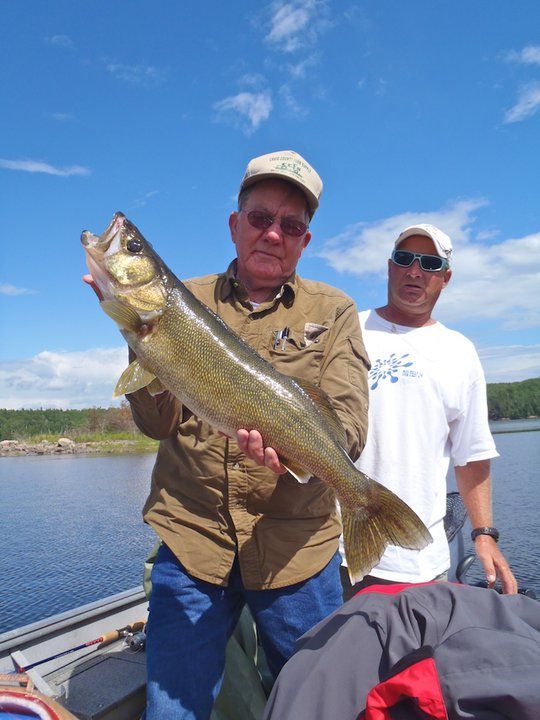 A bright sunny day with blue skies and our guest is posed for a picture with his walleye.